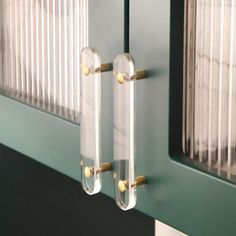 two glass door handles on a green cabinet