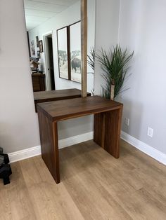 a wooden table sitting in front of a mirror on top of a hard wood floor