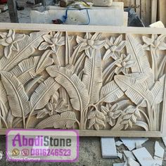 an intricately carved wooden panel with flowers and leaves on the outside, surrounded by concrete blocks