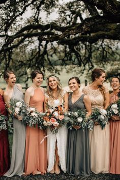 a group of women standing next to each other in front of a tree with flowers