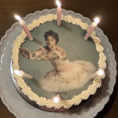 a cake with a photo of a ballerina on it and lit candles in the middle