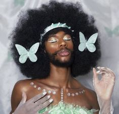 a woman with an afro and butterfly hairpiece on her head is posing for the camera