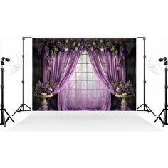 an image of a purple backdrop with curtains and flowers on the window sill in front of it