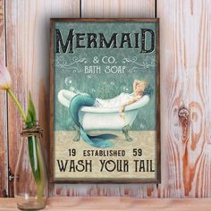 a mermaid bath and soak sign next to a vase with tulips in it