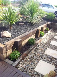 a wooden bench sitting next to a lush green planter filled with lots of plants