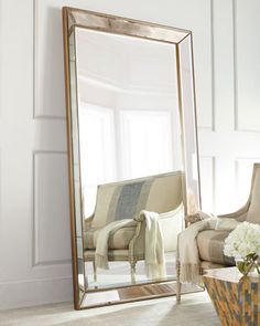 a large mirror sitting on top of a table next to a vase filled with flowers