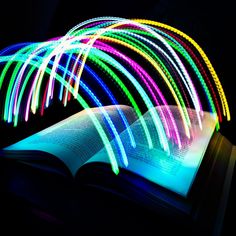 an open book with colorful lights coming out of it