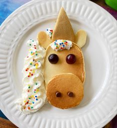 a white plate topped with pancakes covered in icing and a cow face next to a doughnut