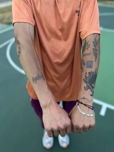 a man with tattoos on his arm standing in front of a basketball court