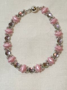 This delicate bracelet is made up of pink and silver back lit gem duo beads.and each gem duo are connect with seed beads and finished with a magnetic clasp Adjustable Pink Beaded Bracelet With Silver Beads, Pink Crystal Bracelet With Round Beads, Pink Crystal Bracelets With Round Beads, Pink Beaded Czech Glass Jewelry, Adjustable Pink Jewelry With Faceted Beads, Pink Spacer Beads Bracelets For Party, Pink Crystal Bracelet With Faceted Beads For Party, Adjustable Double Strand Pink Jewelry, Pink Party Bracelets With Spacer Beads