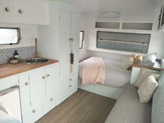 the interior of a camper with white walls and wood flooring