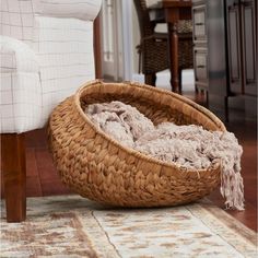 a woven basket sitting on top of a wooden floor next to a chair and rug