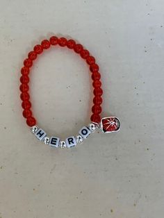 "Support your favorite firefighter with this adorable HERO bracelet. Made with glass red beads, and plastic letters surrounded by silver beads. There is a small enamel fire hat charm hanging from the side.   It stretches to fits up to a 7.5\" wrist.  Comes wrapped in a gift giving bag with tie. In stock items ship within 2-3 business days.  Custom orders can take up to 10 days. Shipping Times - Please allow 3-5  delivery in the U.S.  7-10 business days to Canada and 10-15 business days to Europe Firefighter Bracelet, Hero Bracelet, I Am A Hero, Keychains Ideas, Fire Hat, Vision 2024, Beaded Charm Bracelet, Plastic Letters, Red Beads