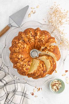 a bundt cake on a glass platter with nuts and a knife next to it