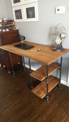 a wooden desk sitting on top of a hard wood floor next to a white wall