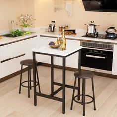 a small kitchen with white cabinets and black bar stools in front of the counter