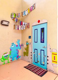 a room with a blue door and some books on the shelves above it that have monsters painted on them