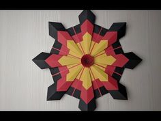 a red and yellow paper flower on a white wall