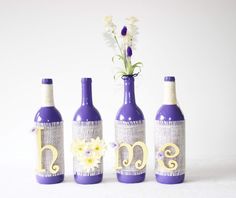 three wine bottles with flowers in them sitting next to each other