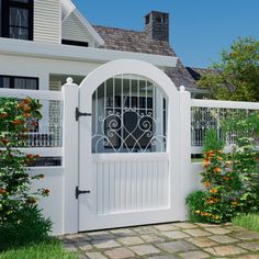 a white gated entrance to a house with flowers and shrubs around it in the front yard