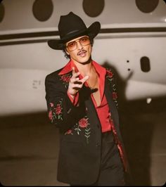 a man in a black suit and red shirt with a cowboy hat on his head