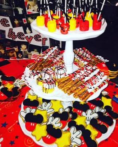 a mickey mouse themed dessert table with cookies and snacks on it's platter