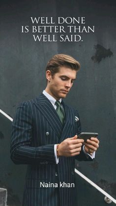 a man in a suit is looking at his cell phone while standing next to stairs