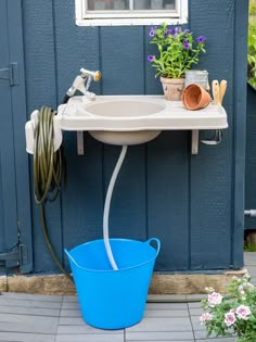 a blue bucket sitting next to a white sink on top of a wooden floor in front of a blue wall