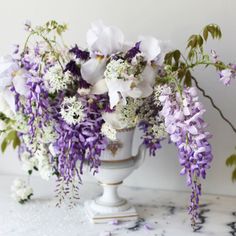 a white vase filled with purple and white flowers