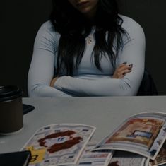 a woman is sitting at a table with her arms crossed and looking over her shoulder