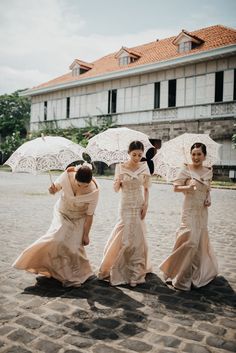 three bridesmaids are walking in the rain with umbrellas over their heads and dresses on