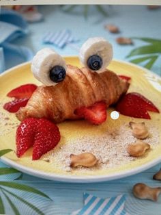 a croissant on a plate with strawberries and nuts in the shape of eyes