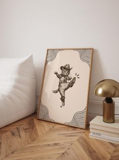 a black and white drawing of a cow in a cowboy hat is on the floor next to a lamp