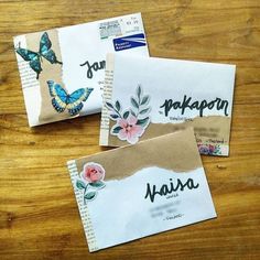 two envelopes with butterflies on them sitting on top of a wooden table next to each other