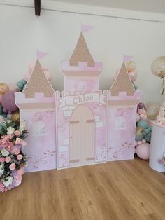 a pink princess castle backdrop with balloons and flowers on the floor in front of it