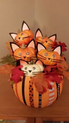 pumpkins decorated with cats and leaves in a basket on top of a wooden table