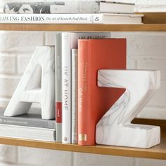 a book shelf with two books and a white marble letter on the top, along with other books