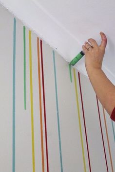 a person is painting the ceiling with colorful stripes on it and holding a paint roller in their hand