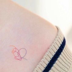 a small heart tattoo on the back of a woman's left side ribcage