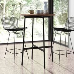 a table with two chairs and a bowl on it in front of a large window