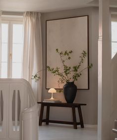 a plant in a vase on a table next to a crib