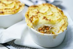 two white dishes filled with food sitting on top of a table next to each other