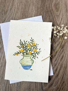 a card with an image of a vase filled with flowers on top of a wooden table