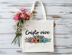 Carry Your Faith in Style: "Cristo Vive" Tote Bag This beautiful "Cristo Vive" (Christ Lives) tote bag perfectly expresses your faith and carries your essentials in style. Features: Uplifting Message: The inspirational message "Si Dios Quiere" is a daily reminder of God's plan and encourages you to trust in His timing. Spacious and Sturdy: Made from durable 100% cotton canvas fabric, this tote is built to last and can comfortably carry all your everyday essentials. Perfect Size: Measuring 15" x 16" (38.1cm x 40.6cm), it's ideal for groceries, books, or anything you need for your day. Simple and Stylish: The classic design with a touch of faith makes this tote a versatile accessory for any outfit. More Than Just a Tote: This tote bag is more than just a way to carry your belongings; it's a Bible Essentials, Christian Gift Shop, Tote Bag Christian, Christian Tote Bags, Floral Tote Bag, Inspiring Message, Christian Woman, Christian Girl, Painted Clothes