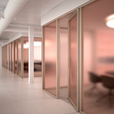 an empty room with pink walls and glass partitions on the wall, in front of a black chair