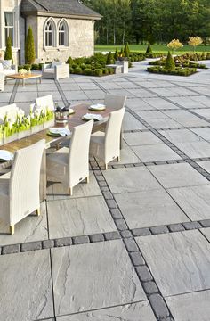 an outdoor dining table and chairs on a patio with stone paversed flooring