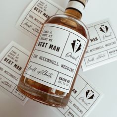 a bottle of groom's best man alcohol sitting on top of some wedding stickers