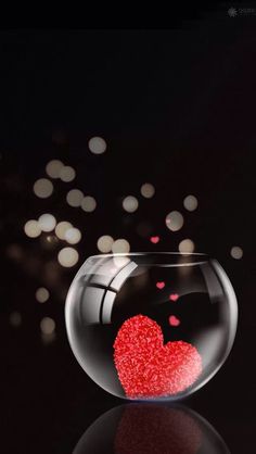 a heart in a fish bowl filled with water and red glitters on the bottom