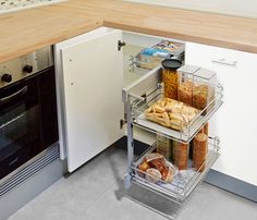 a kitchen with an oven, dish rack and counter top filled with breads on it