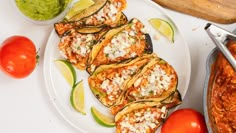 some food is on a white plate with tomatoes and guacamole next to it